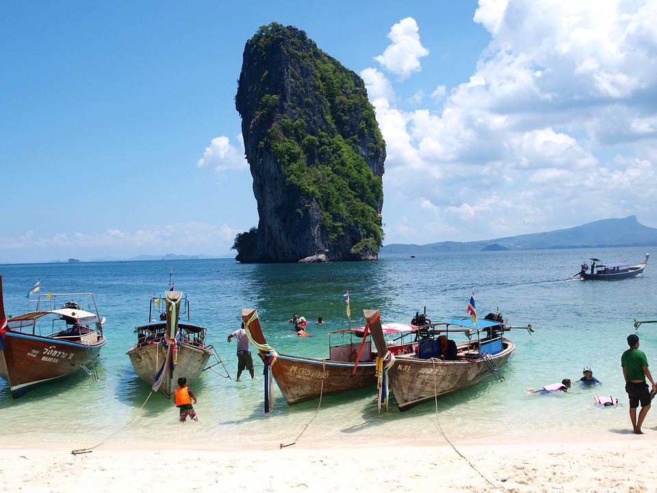 4 longtail boats lined up along in the beach in Krabi, Thailand