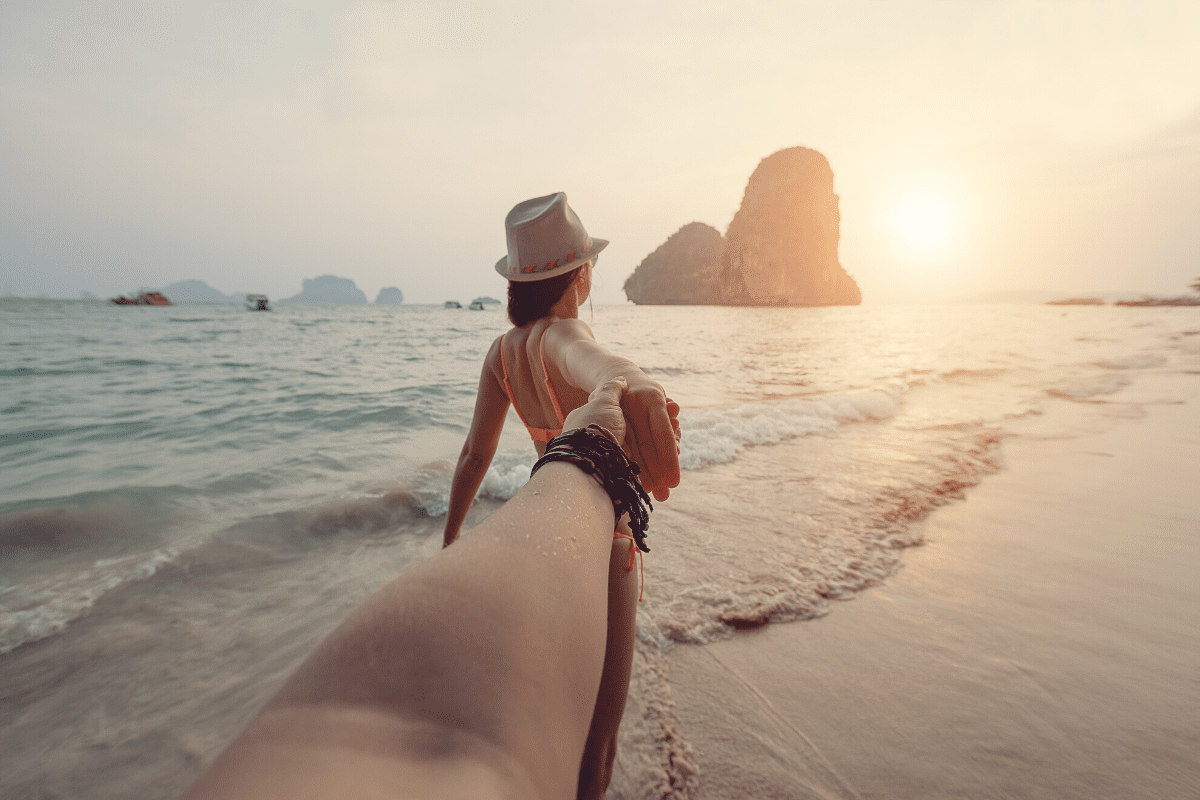 pov of a man holding a eomands hand. she is stanidng in the sea in Railay's beach looking out towards Krabi's islands