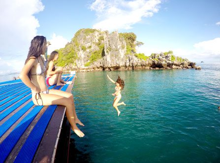 Image of guests on boat and jumping into water during a Krabi Private Morning Cruise with islands in the background