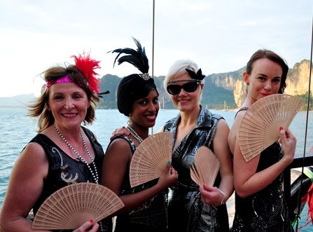 Group of guests dressed up and posing with fans onboard a Private Cruise in Krabi with sea and islands in the background