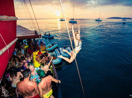 Girl jumping off a packed party boat during Private Cruise in Krabi at sunset with yachts in the background