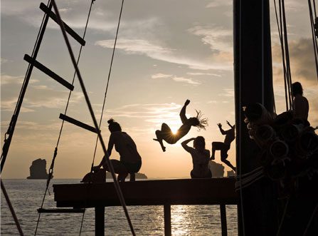 Silhouette of guests onboard and jumping off boat at sunset during Krabi Sunset Cruise