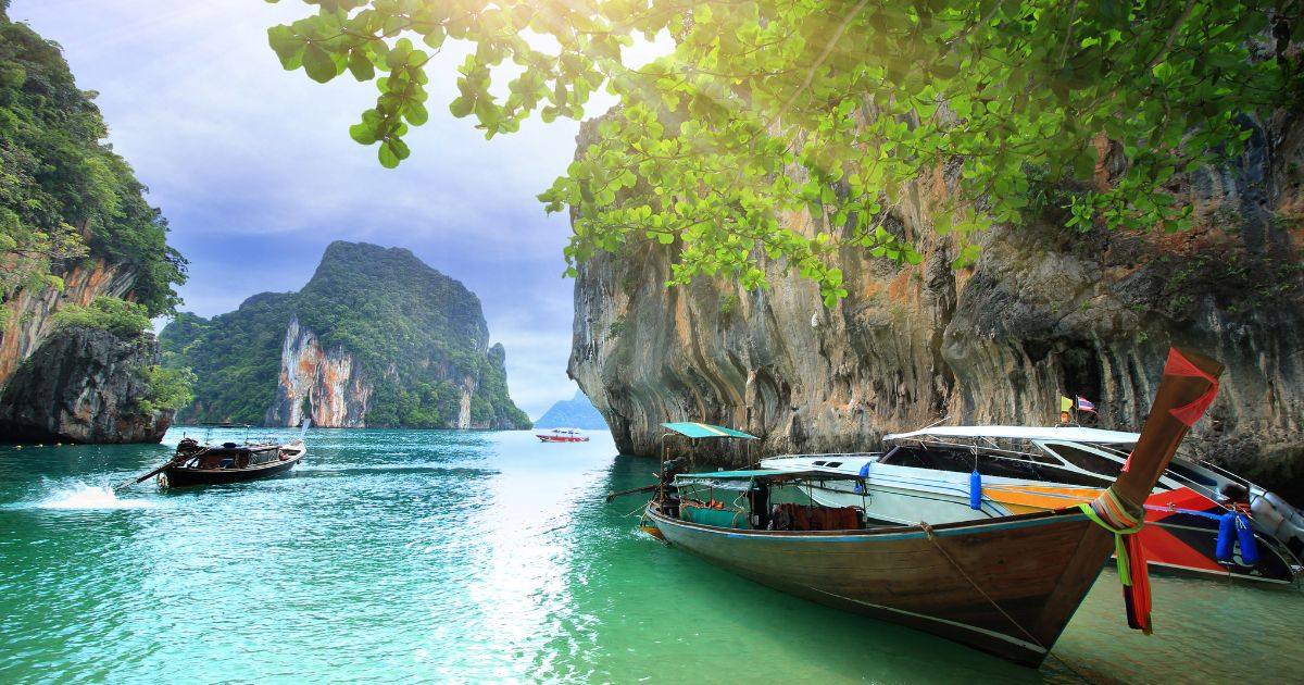 Boat at Railay beach with rocky cliffs in background