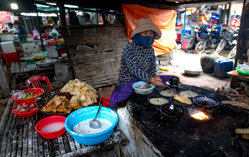 señora preparando comida tailandesa en un gran plato caliente en un mercado
