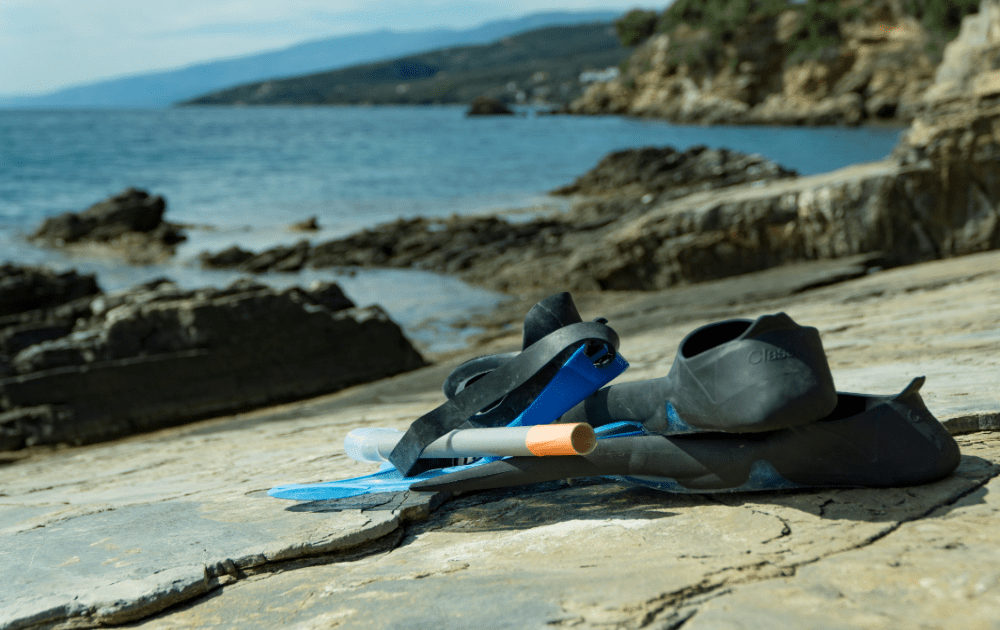 snorkel and mask resting on a rock with sea views in the background