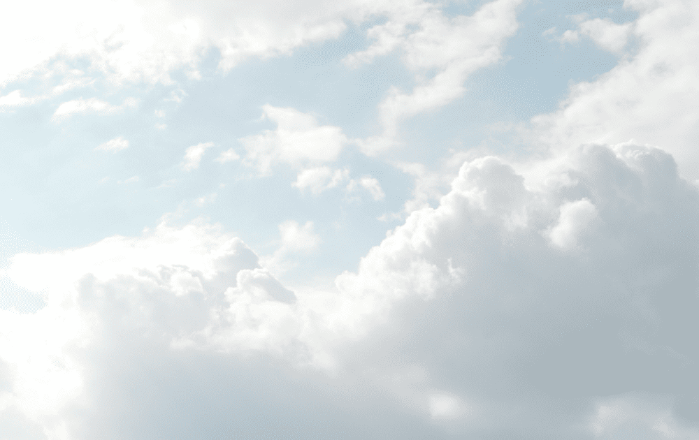 Fluffy clouds with a pale blue backdrop