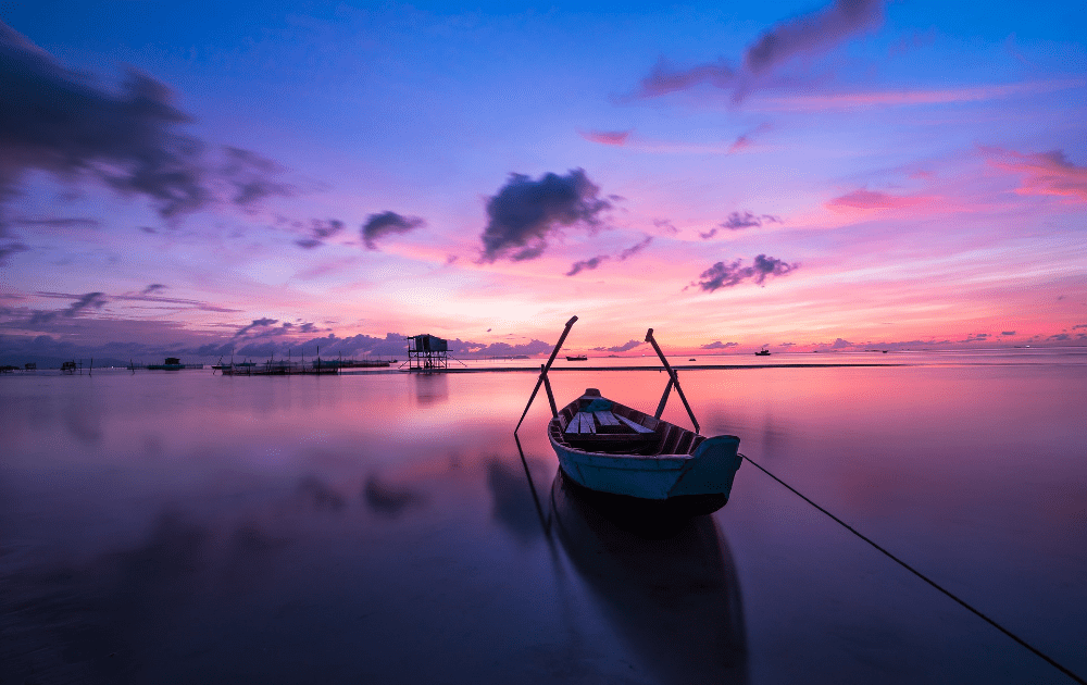 Puesta de sol púrpura y rosa en Tailandia con un pequeño barco al frente