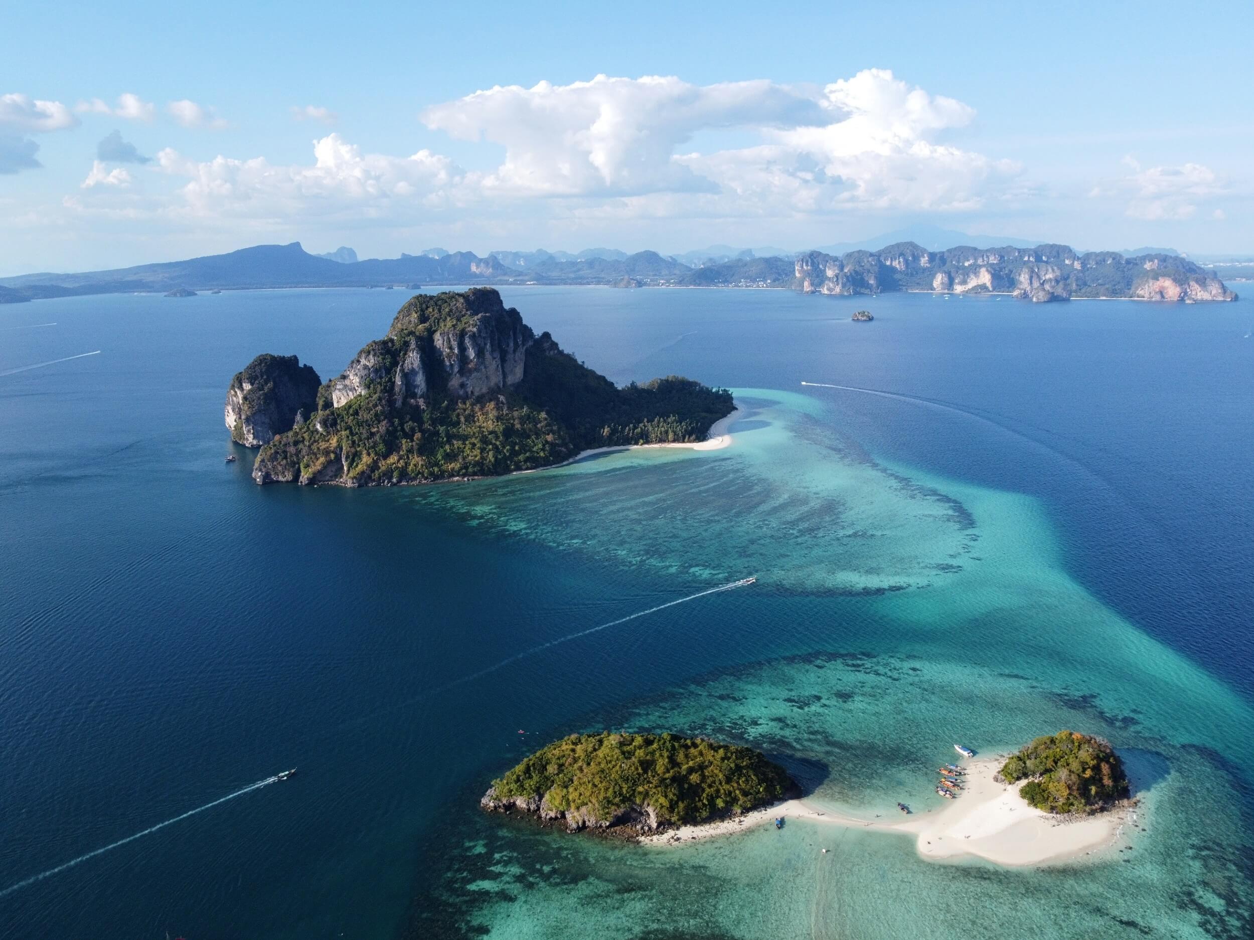 Krabi drone photography - blue waters with two islands with sandy beach in the foreground