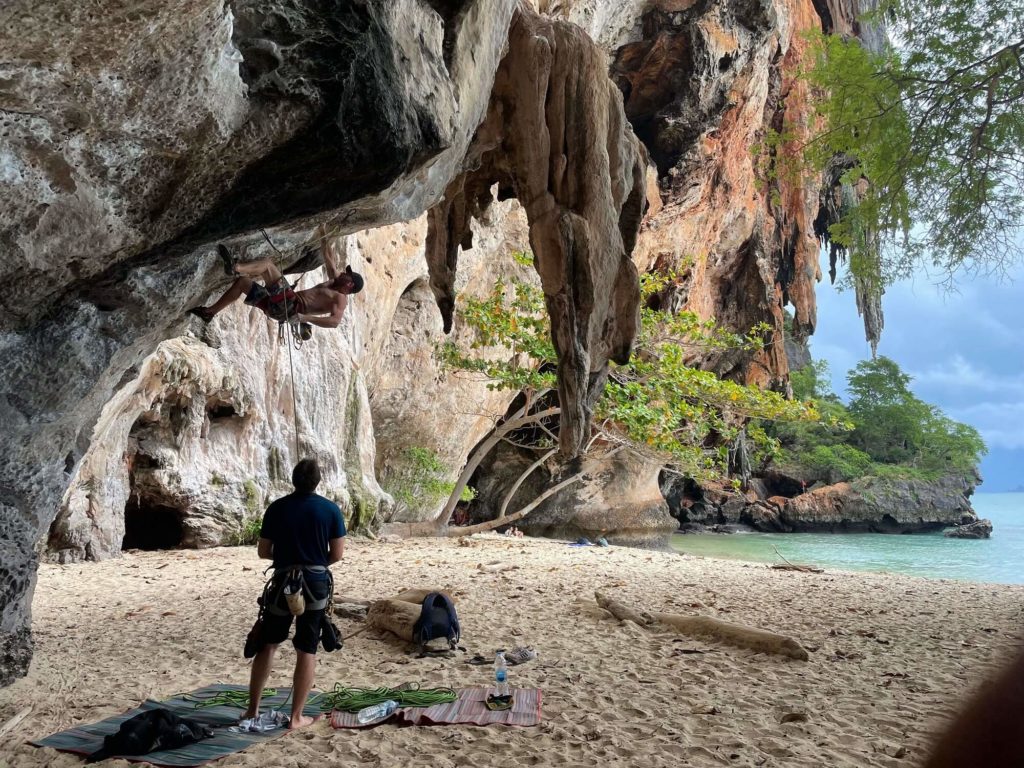 A Rock climber on Railay Pranang Beach setting up their ropes under an overhang