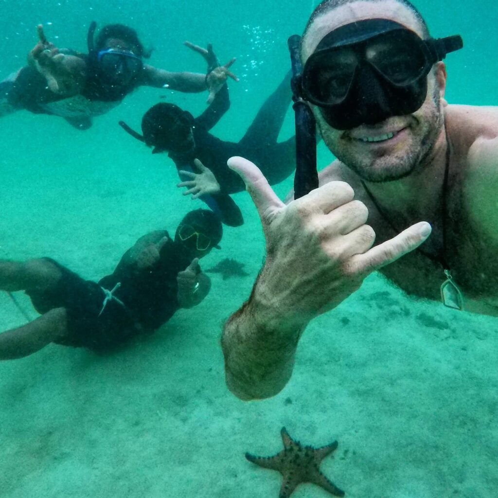 four snorkel freedivers taking a selfie with a lagre starfish at the bottom of the sea in krabi
