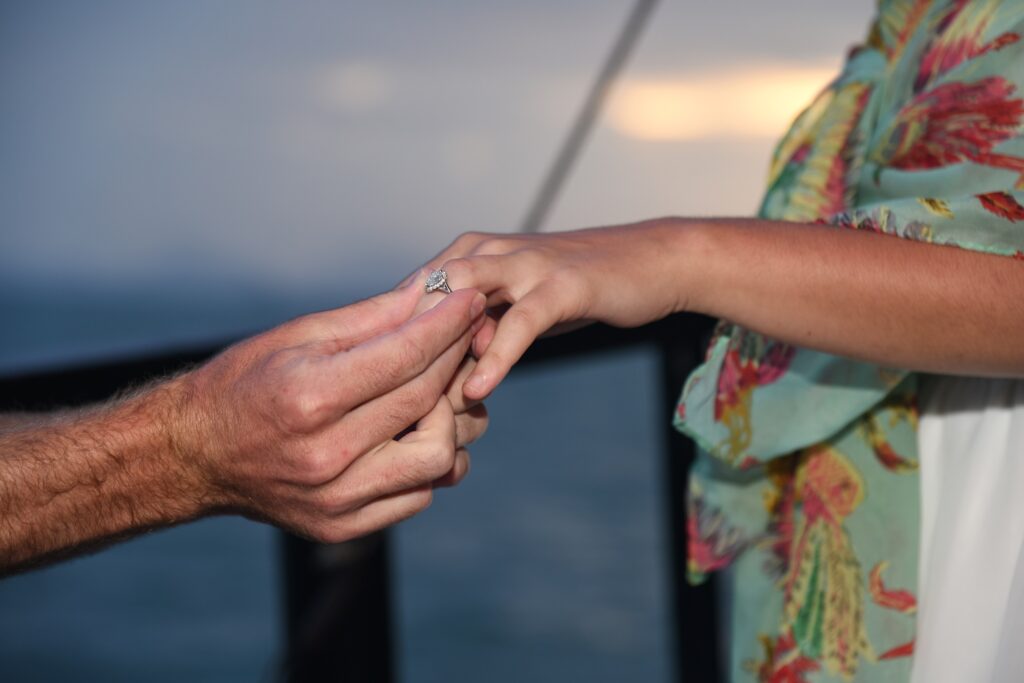 placing a wedding ring on a finger with the sunset in the background