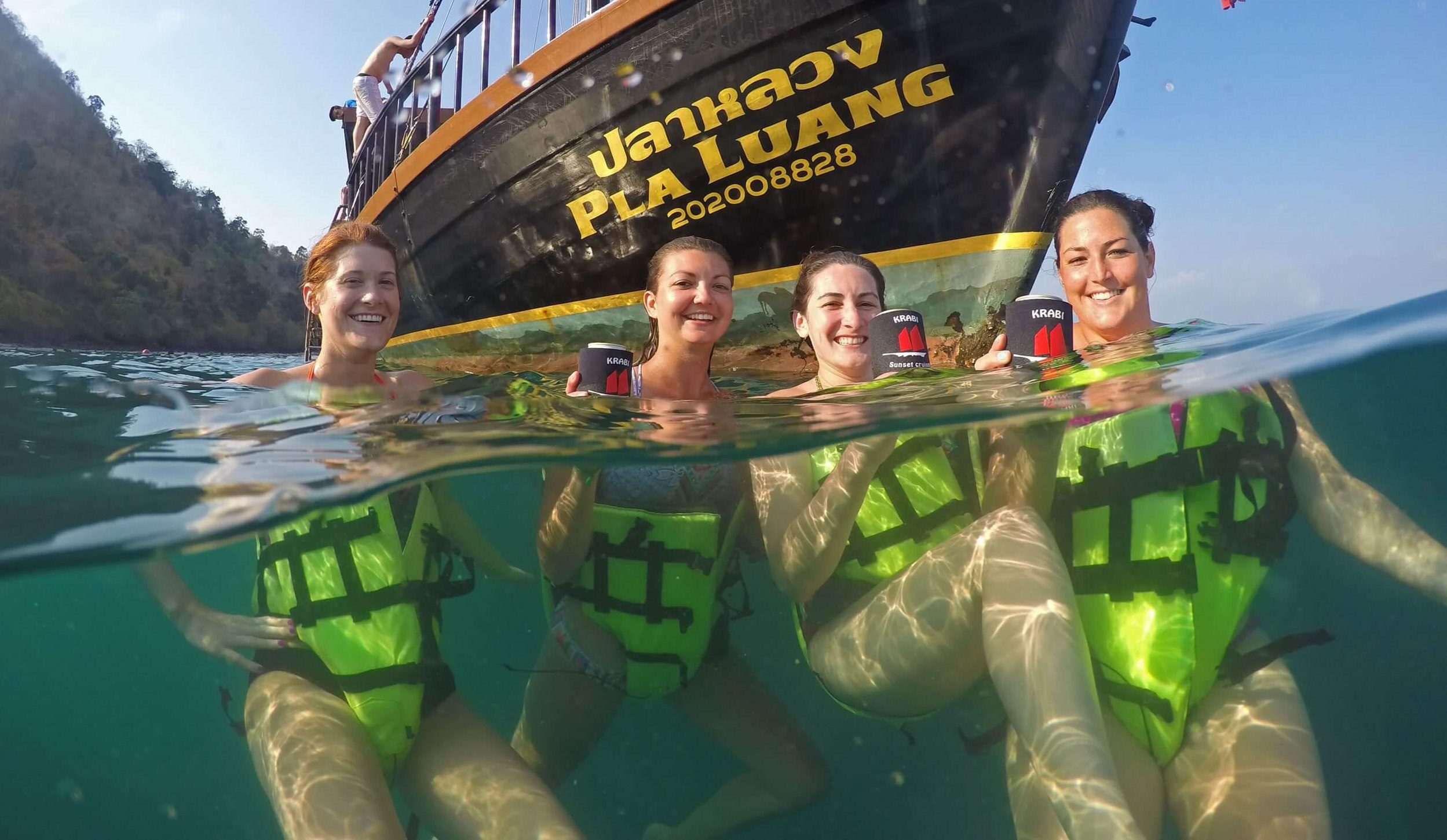 4 people in the water with krabi sunset cruises boat in the background