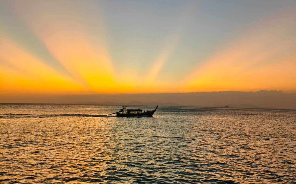 a longtail boat on the water near aonang beach during sunset