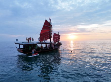 Sunset cruise on a red-sailed junk boat with guests swimming and paddleboarding in Krabi