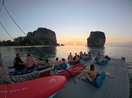 Invités se relaxant sur le pont d'une jonque tout en regardant le coucher de soleil entre les îles calcaires de la plage de Poda.