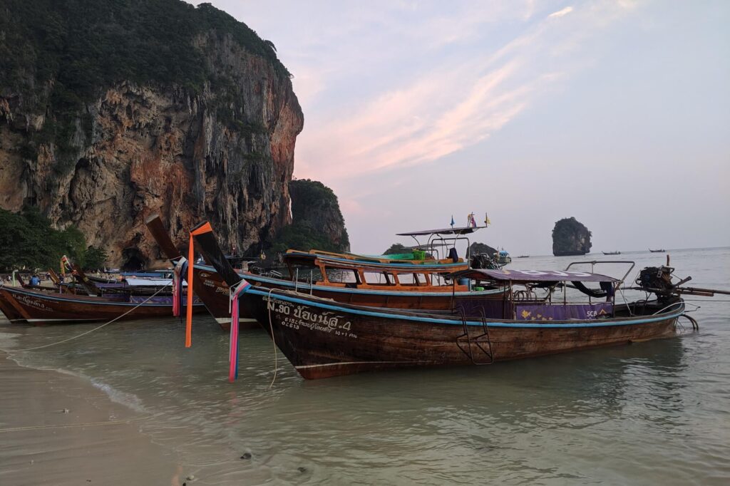 longtail boats waiting by the shore in railay at sunset