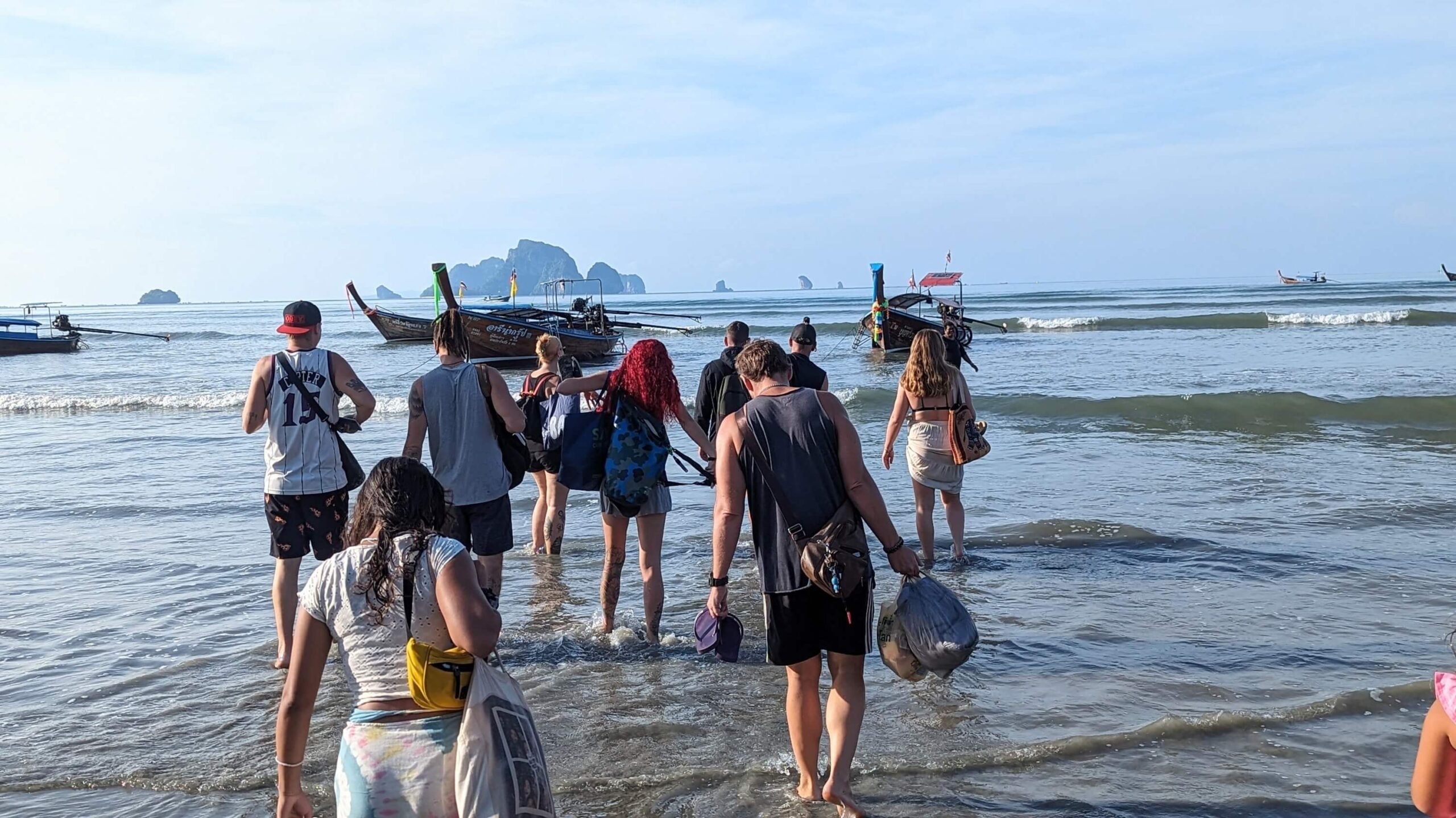 group of people wading into the water to a longtail boat in krabi