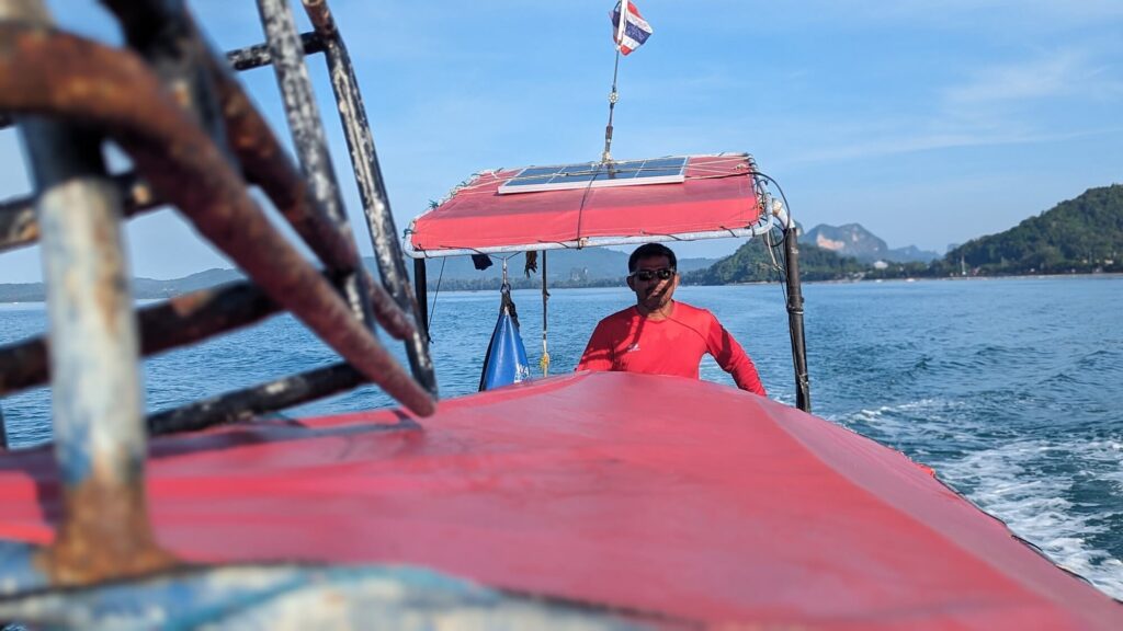 looking down the top of a longtail boat towards the driver at the back
