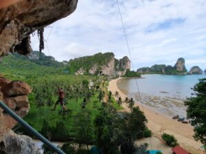 vistas sobre la playa de tonsai desde los acantilados con un escalador colgado en el espacio abierto
