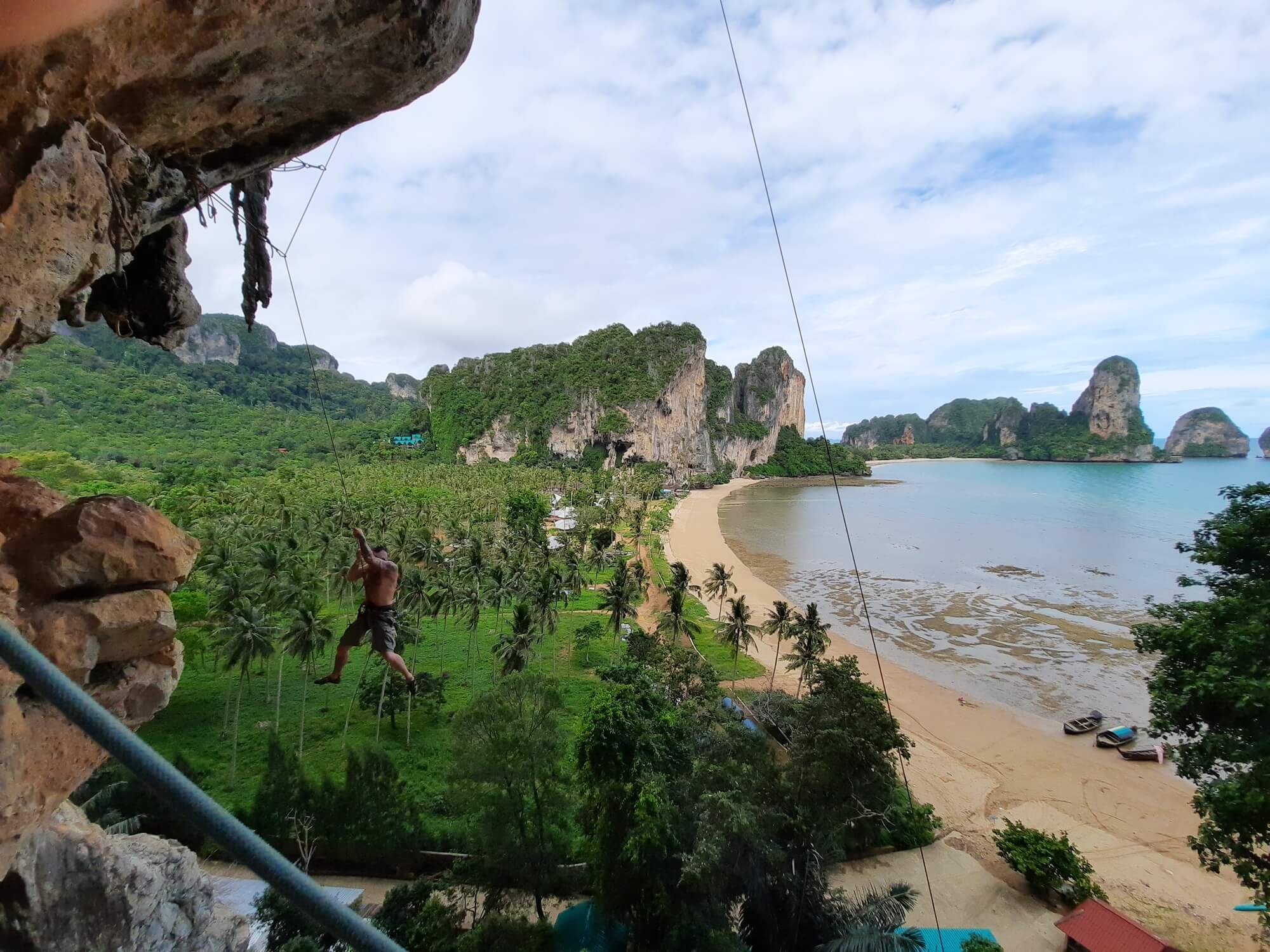 vue sur la plage de tonsai depuis les falaises avec un grimpeur suspendu dans l'espace ouvert