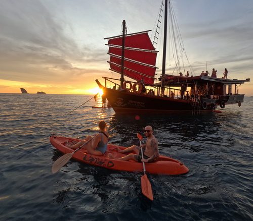 Kayaking at sunset with a junk boat in the background