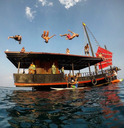 3 people jumping from the roof of krabi sunset cruises junk boat