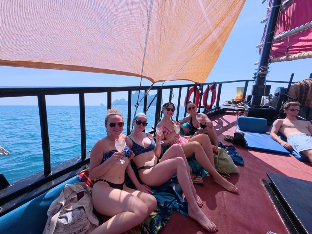 4 girls with cocktails in bikinis lounging on a boat deck in thailand