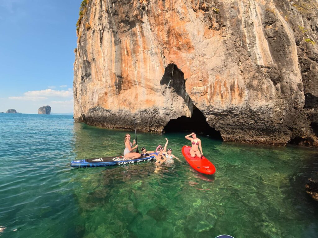 paddle boarders in front of a cave in the waters of krabi